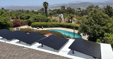 Solar panels on a San Diego home overlooking palm trees, a pool and the mountains